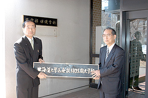 看板を外す中村学長,松野部長