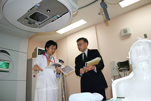 動体追跡照射装置の説明を受ける土屋審議官(右)