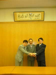 協定書調印後,握手する菅原喜茂別町長(中央),中村公共政策大学院長(右側)及び山崎教授(左側)