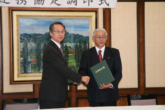 協定書調印後,握手するコ永哲雄弟子屈町長(右)と上田一郎農学研究院長