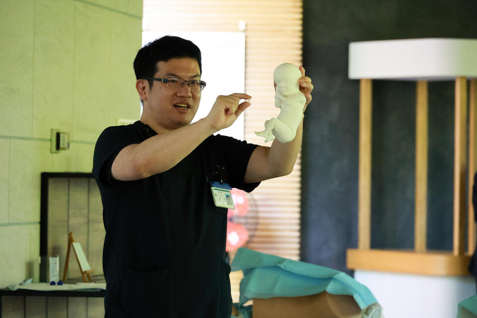 胎児の模型を使って説明する玉城医師
