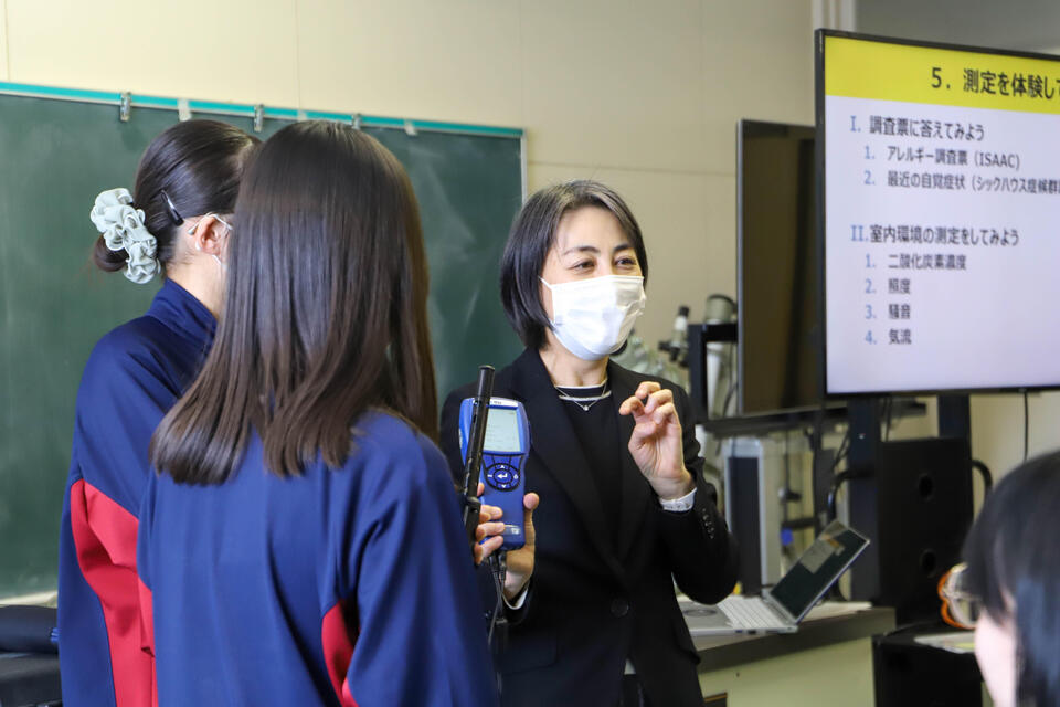 測定機械を使って生徒たちに室内の測定を体験させる池田教授