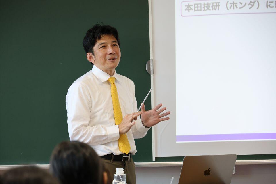 卒業生の活躍について話す菊地教授